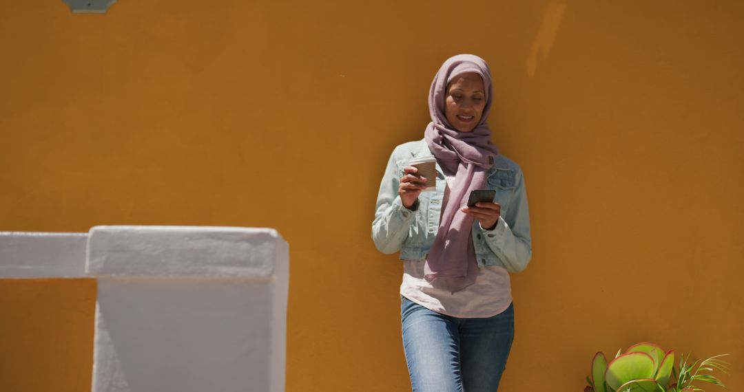 Smiling Woman in Hijab Using Smartphone Against Bright Yellow Wall - Free Images, Stock Photos and Pictures on Pikwizard.com