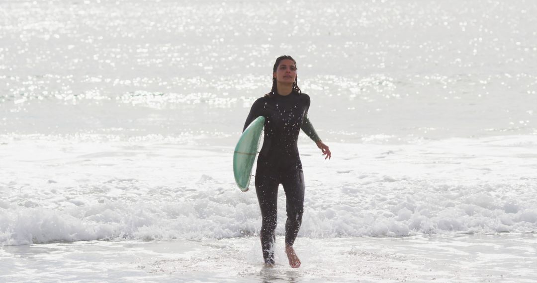 Surfer Walking Out of the Water Carrying Surfboard in Wetsuit - Free Images, Stock Photos and Pictures on Pikwizard.com