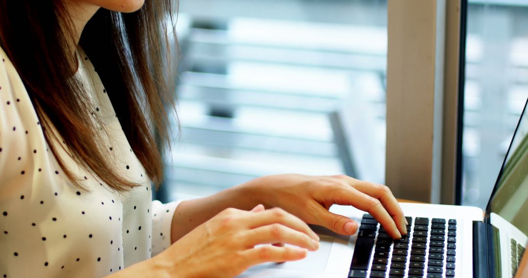 Woman Typing on Laptop by Window in Office - Free Images, Stock Photos and Pictures on Pikwizard.com