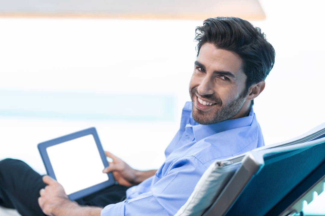 Smiling Man with Digital Tablet Seated on Lounge Chair Exudes Relaxation