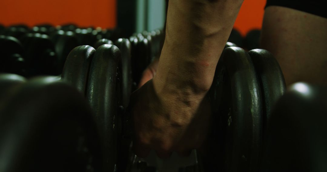 Close-up view of arm reaching for dumbbell in gym - Free Images, Stock Photos and Pictures on Pikwizard.com