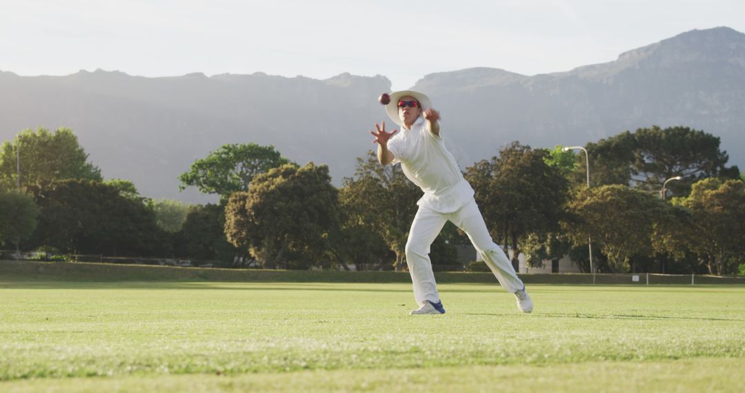 Cricket Player Catching Ball on Field with Mountain Background - Free Images, Stock Photos and Pictures on Pikwizard.com