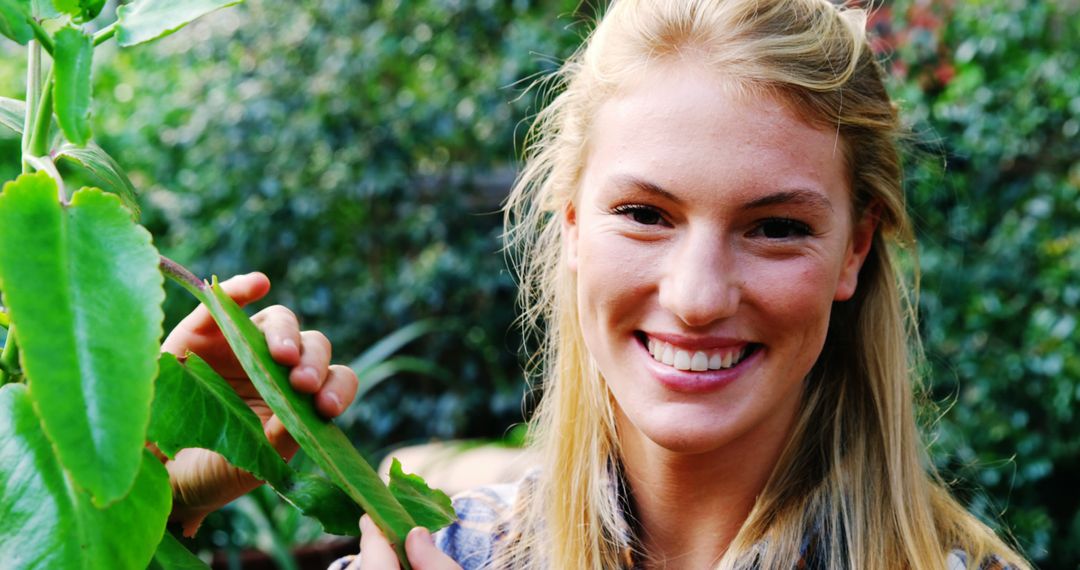 Smiling Young Woman Holding Leaf in Lush Greenery - Free Images, Stock Photos and Pictures on Pikwizard.com