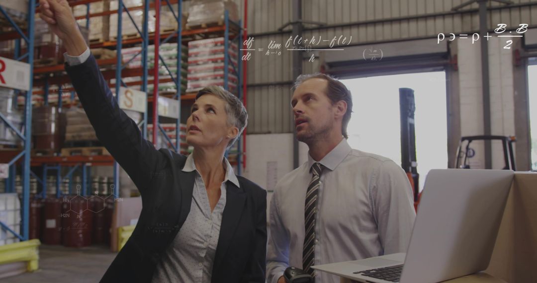 Warehouse Supervisor Pointing While Training Team Member with Scanner and Laptop
