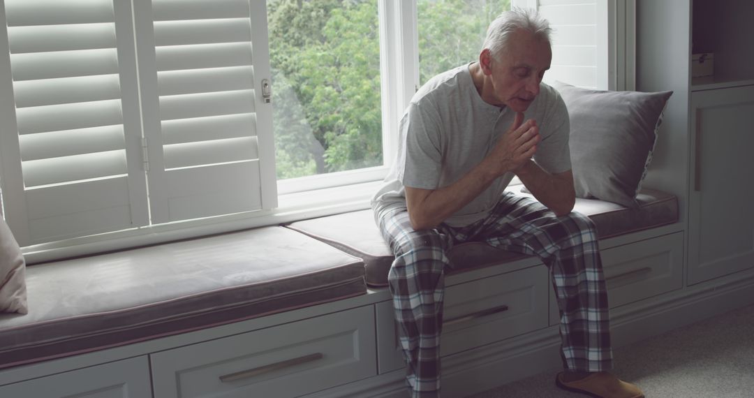 Elderly Man Reflecting by Window Seat in Comfortable Home - Free Images, Stock Photos and Pictures on Pikwizard.com