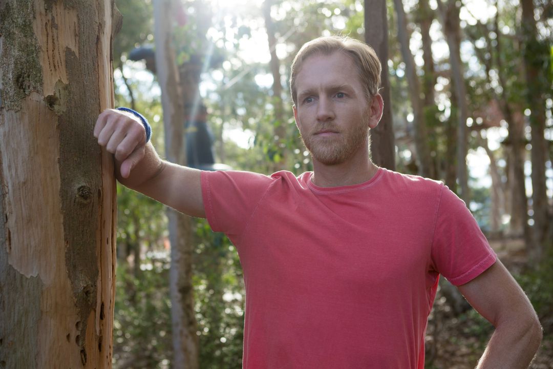 Man Standing in Forest Leaning Against Tree - Free Images, Stock Photos and Pictures on Pikwizard.com