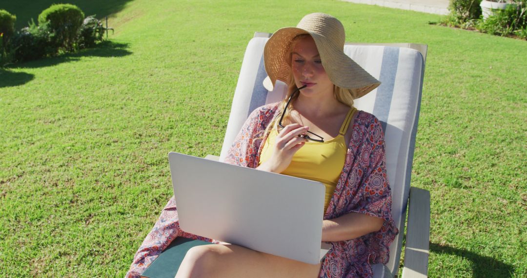 Woman Relaxing Outside Wearing Sun Hat Working on Laptop - Free Images, Stock Photos and Pictures on Pikwizard.com