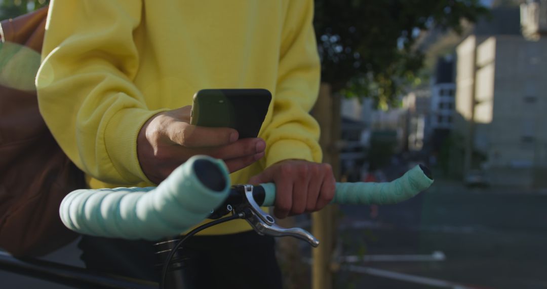 Person holding phone while standing next to bicycle handlebars - Free Images, Stock Photos and Pictures on Pikwizard.com