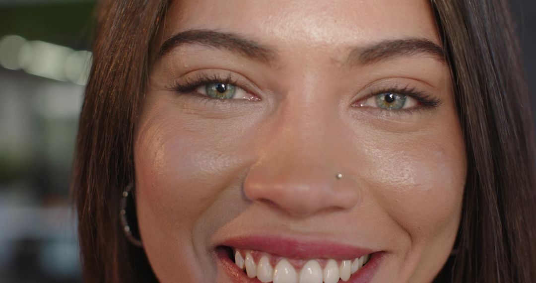 Smiling Indian woman in twenties showing nose stud and hoop earring close-up portrait
