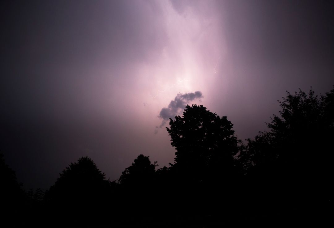 Moody Sky with Lightning Over Silhouetted Trees During Storm - Free Images, Stock Photos and Pictures on Pikwizard.com