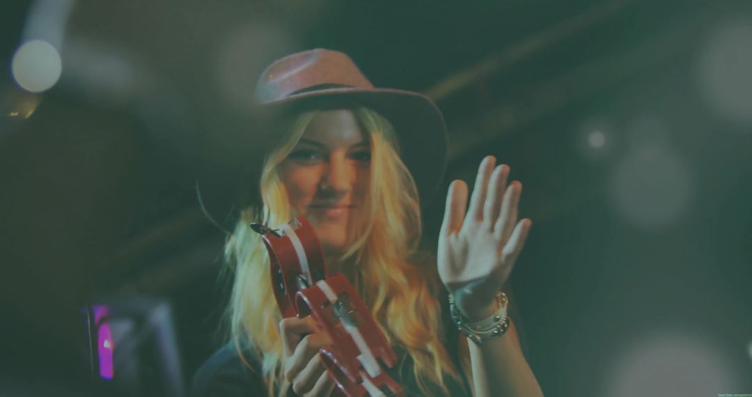 Energetic Performer at Concert with Tambourine and Hat