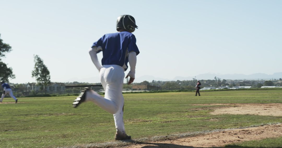 Youth Baseball Player Running on Field Under Sunny Sky
