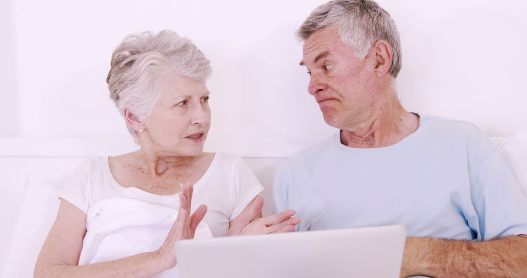 Senior Couple Discussing While Using Laptop in Bed - Free Images, Stock Photos and Pictures on Pikwizard.com