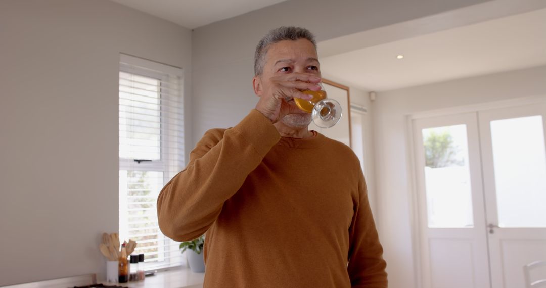 Senior Man Enjoying Refreshing Beer in Bright Home Kitchen