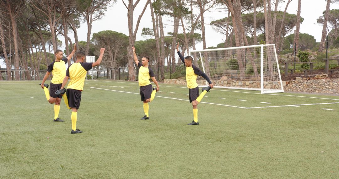 Soccer Players in Yellow Uniforms Stretching on Field
