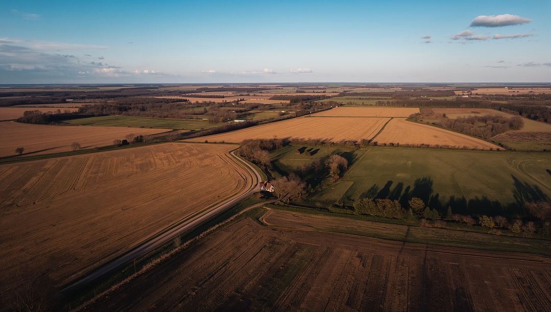 Farmhouse Nestling on Curved Track Casting Long Shadows Over Golden Farmland