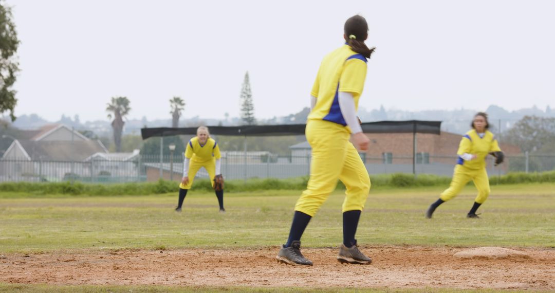 Female Softball Players in Yellow Uniforms on Mound During Pitch