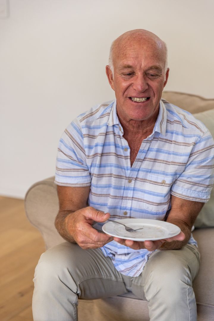 Senior Man Holding Empty Plate With Displeased Expression