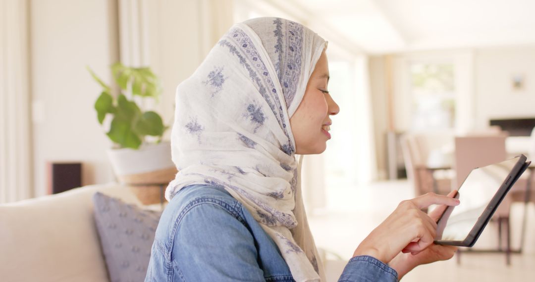 Smiling Woman in Hijab Using Tablet at Home - Free Images, Stock Photos and Pictures on Pikwizard.com