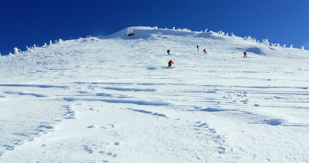 Skiers Descending Snow-covered Mountain Slope on Bright Sunny Day - Free Images, Stock Photos and Pictures on Pikwizard.com