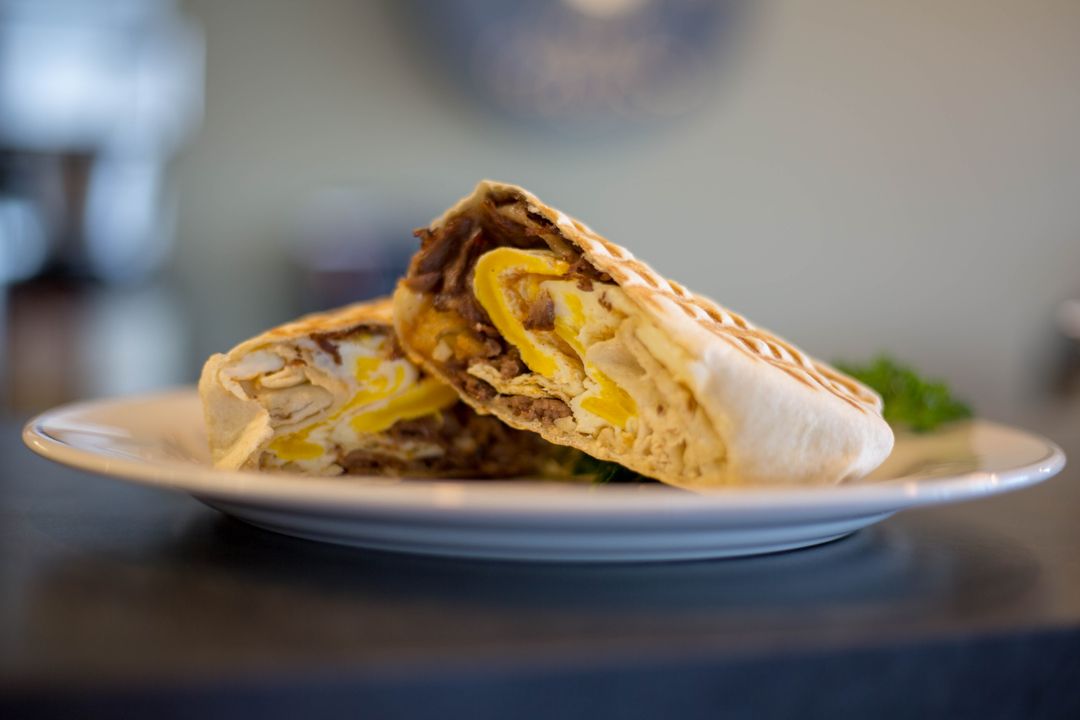 Hearty steak and egg breakfast wrap grilling golden, sliced and served on white plate