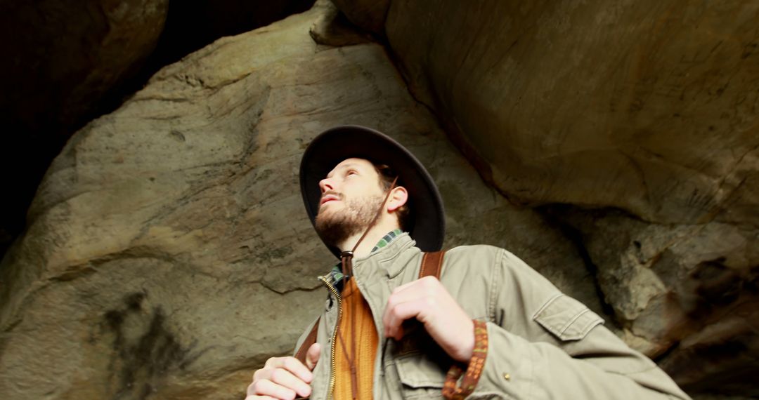 Man Trekking Rocky Mountainside Exploring Cave Journey
