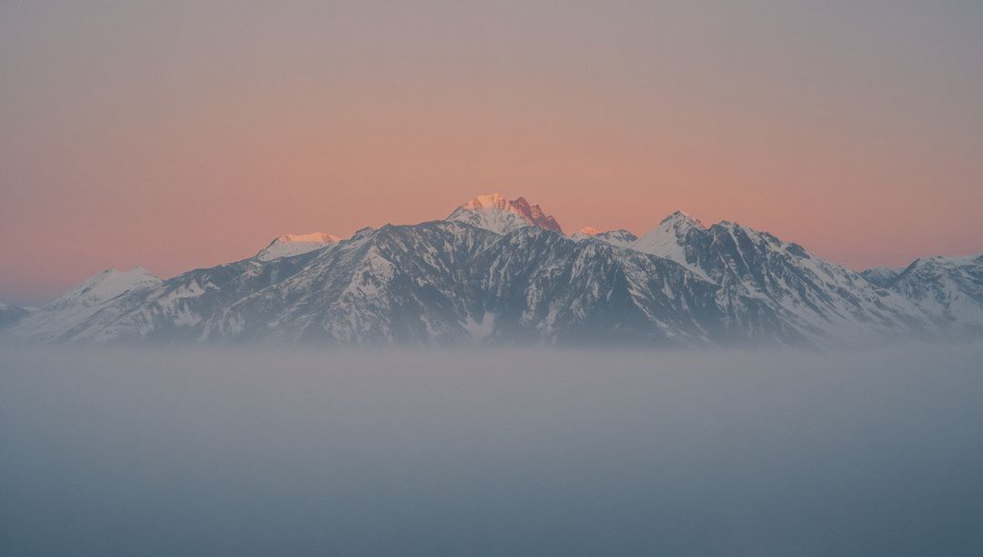 Sunrise Over Misty Snow-Covered Mountain Peaks