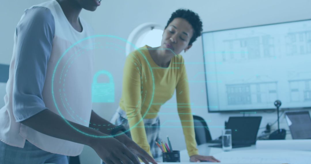 Businesswomen Collaborating Over Digital Security in Modern Office Space