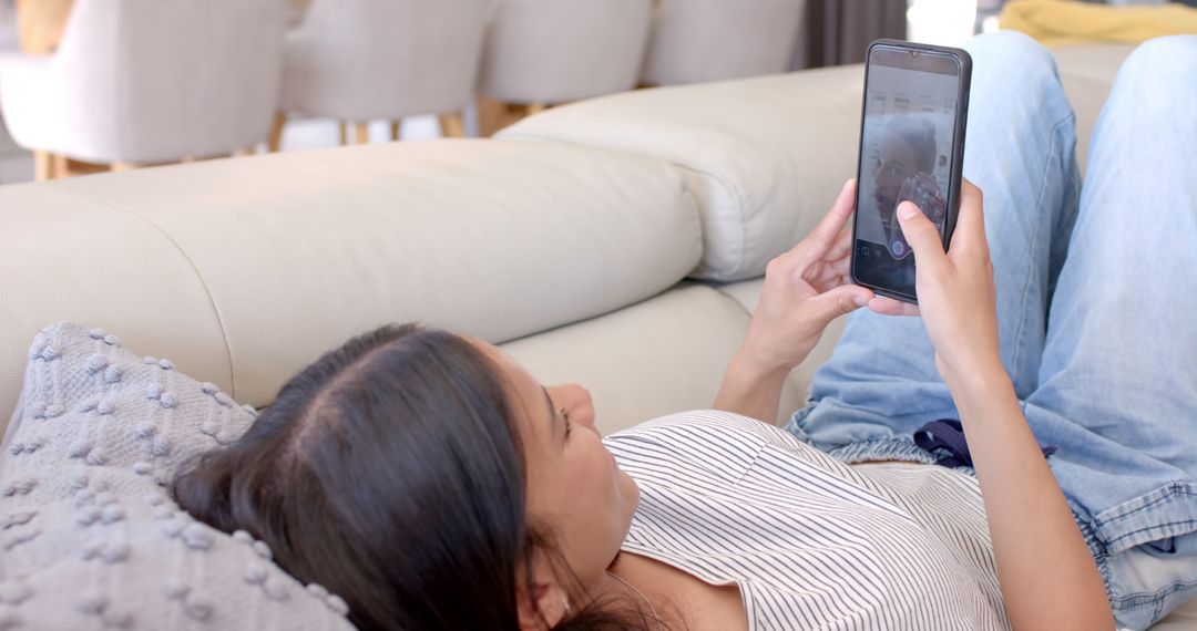 Teenage Girl Relaxing on Couch Using Smartphone at Home