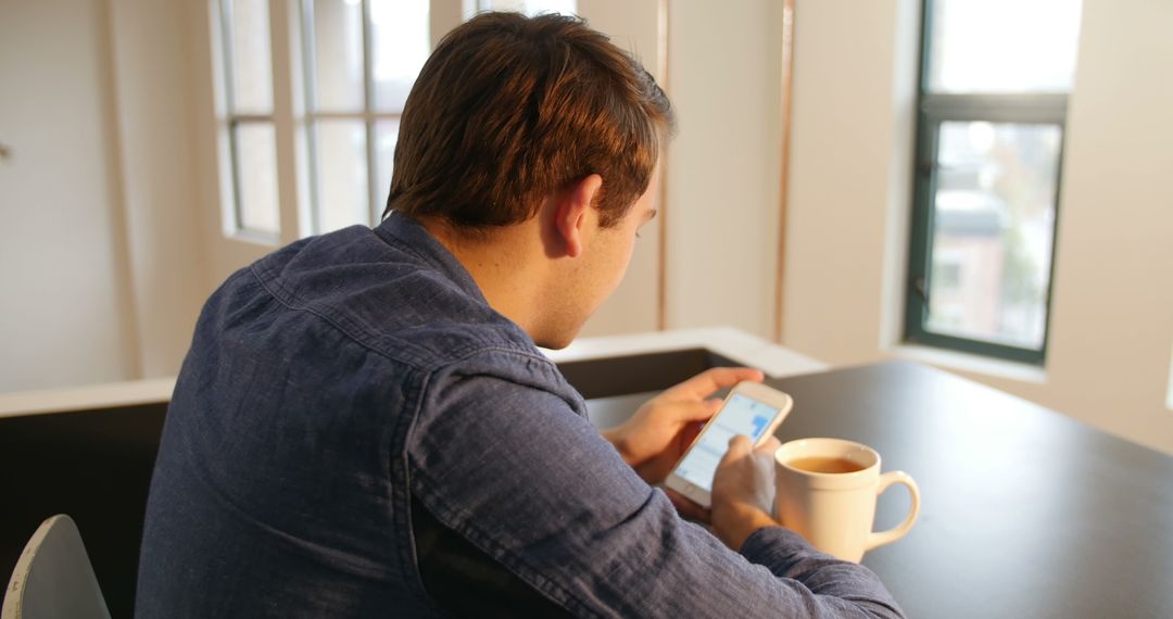 Man Using Smartphone with Coffee Indoors for Relaxation