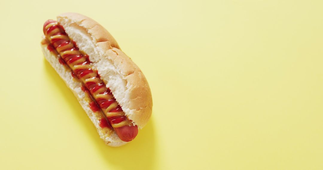 Image of hot dog with mustard and ketchup on a yellow surface - Free Images, Stock Photos and Pictures on Pikwizard.com