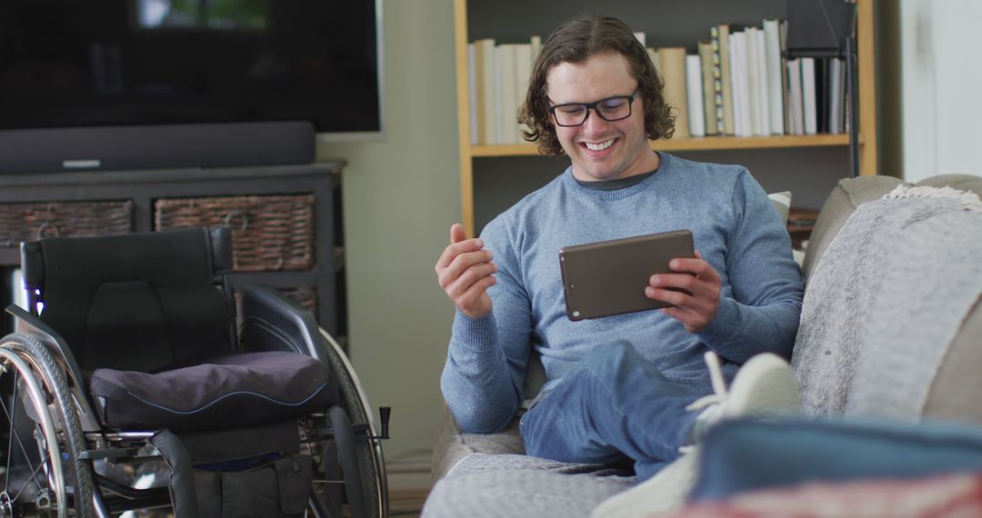 Man in Wheelchair Enjoys Tablet on Sofa - Free Images, Stock Photos and Pictures on Pikwizard.com