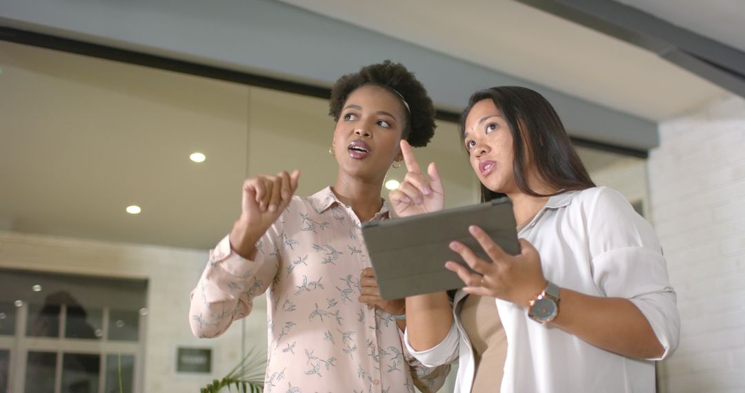 Women Discussing Project with Tablet in Modern Office