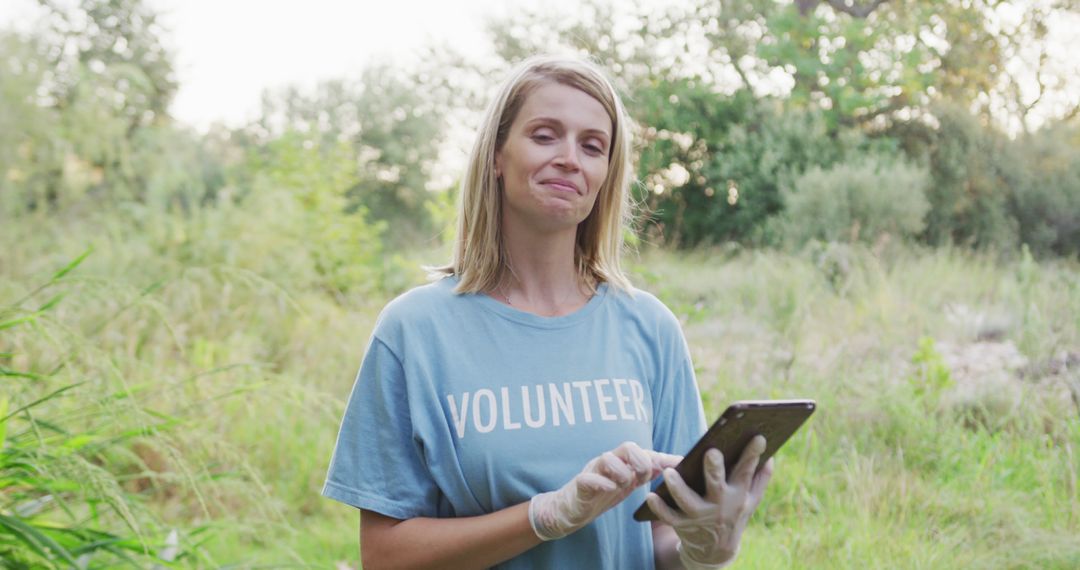 Happy Female Volunteer Using Tablet in Nature - Free Images, Stock Photos and Pictures on Pikwizard.com