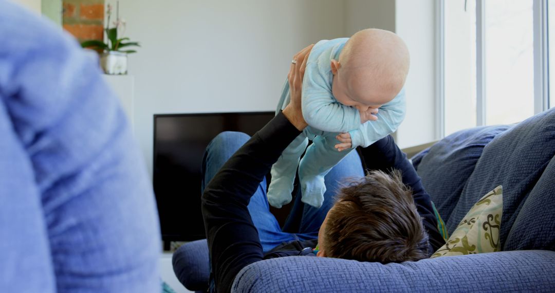 Father Lifting and Playing with Infant in Living Room - Free Images, Stock Photos and Pictures on Pikwizard.com