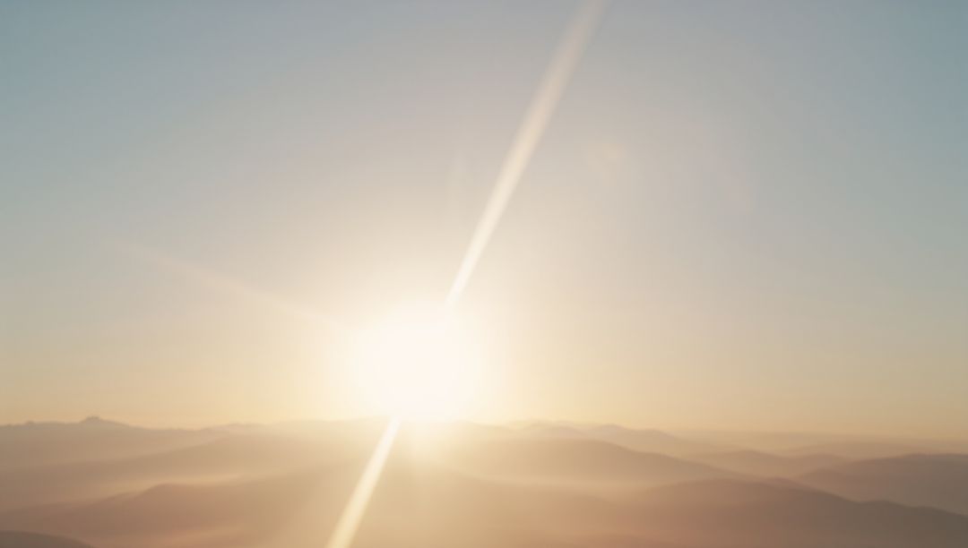 Serene Sunrise Over Misty Mountain Ridges with Soft Rays