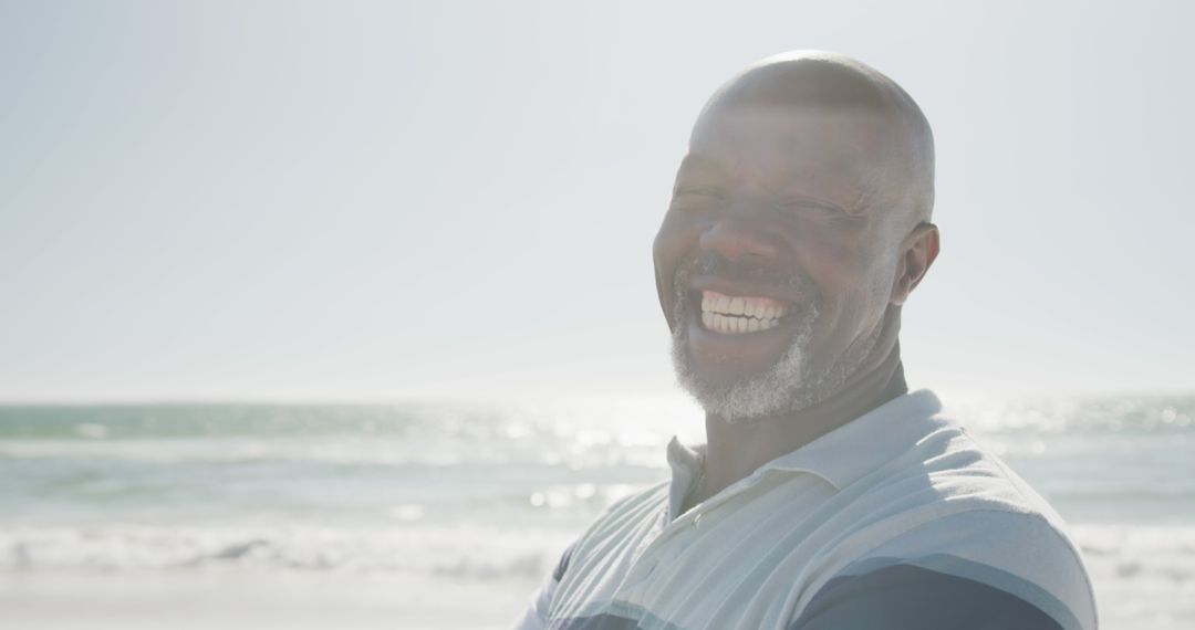 Elderly Man Smiling Joyfully by Ocean on Sunny Day - Free Images, Stock Photos and Pictures on Pikwizard.com