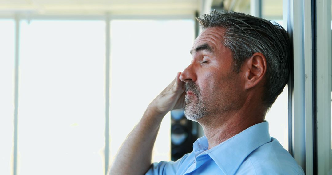 A middle-aged man seems stressed, possibly with a headache, as he pinches his nose. - Free Images, Stock Photos and Pictures on Pikwizard.com