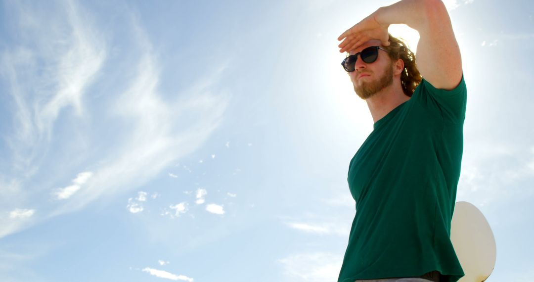 Man Gazing at Sky Wearing Green Shirt and Sunglasses on Sunny Day - Free Images, Stock Photos and Pictures on Pikwizard.com