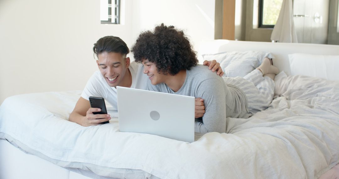 Smiling Couple Browsing Devices Together in Cozy Bedroom