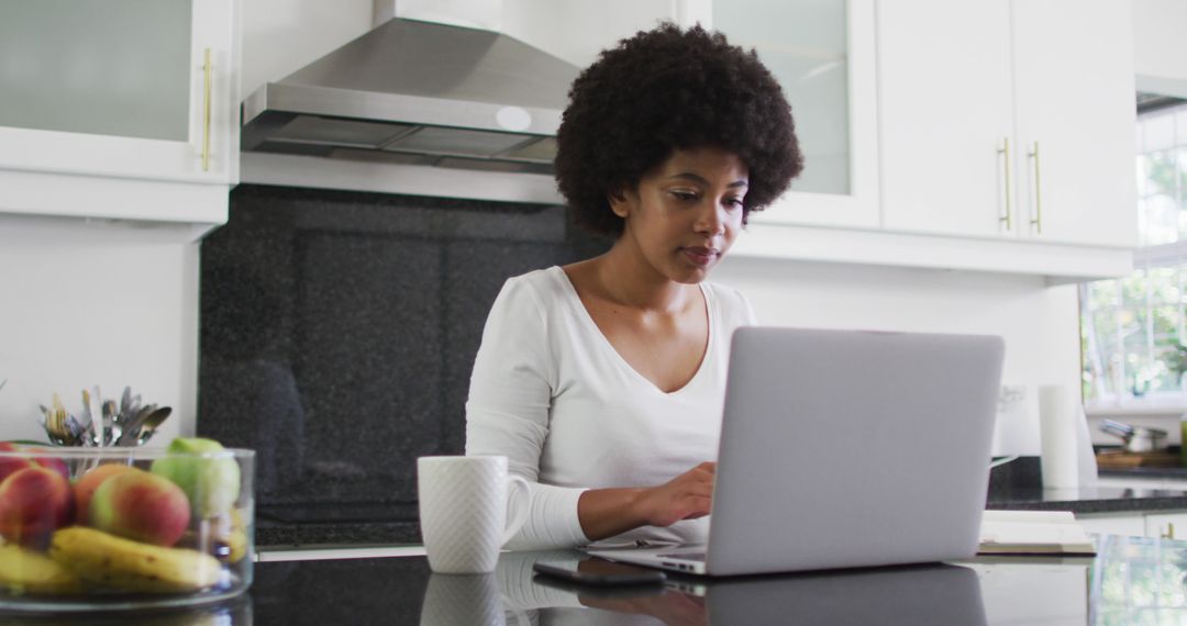 African american woman using laptop in the kitchen while working from home - Free Images, Stock Photos and Pictures on Pikwizard.com