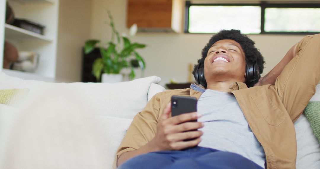 Relaxed Man Enjoying Music with Smartphone and Headphones at Home
