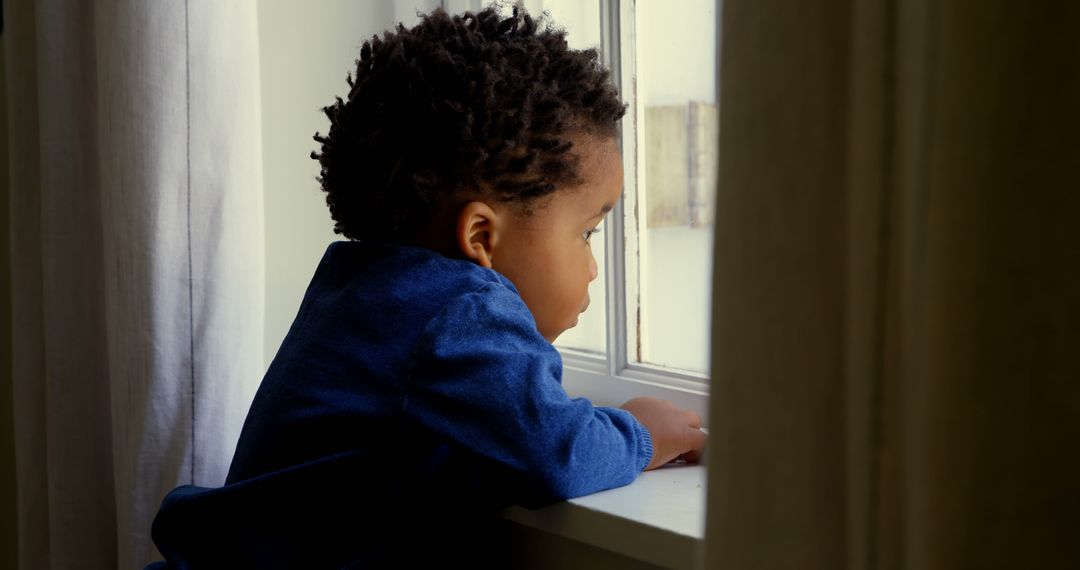 Side view of cute little black boy leaning on window sill in a comfortable home - Free Images, Stock Photos and Pictures on Pikwizard.com