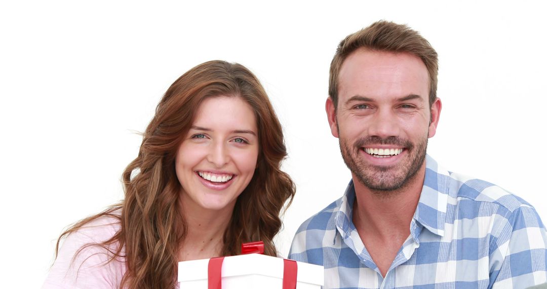 A young Caucasian woman and man are smiling brightly, holding a gift together, with copy space - Free Images, Stock Photos and Pictures on Pikwizard.com