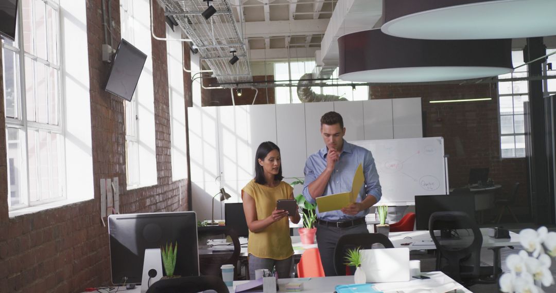 Diverse Colleagues Analyzing Documents in Modern Office Environment