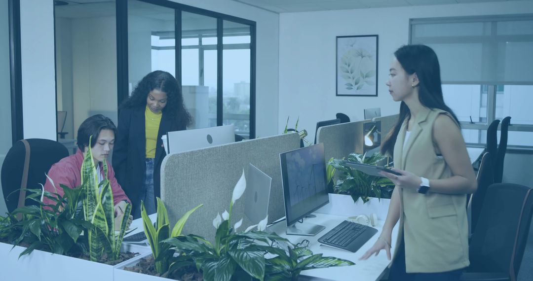 Coworkers Collaborating in Modern Open-Plan Office with Laptops and Tablets