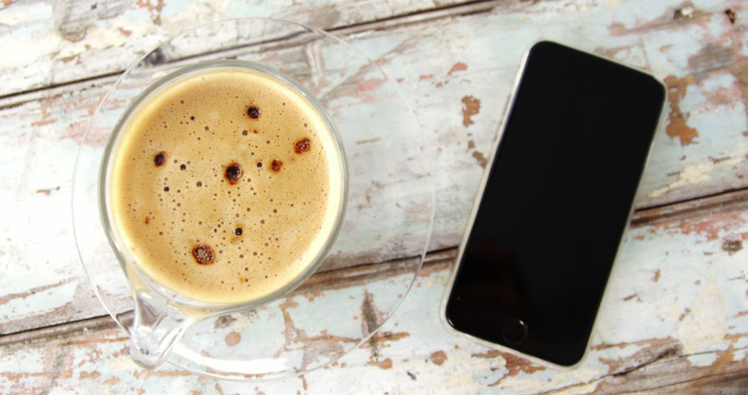 A cup of freshly brewed coffee sits next to a smartphone on a rustic wooden table, with copy space - Free Images, Stock Photos and Pictures on Pikwizard.com