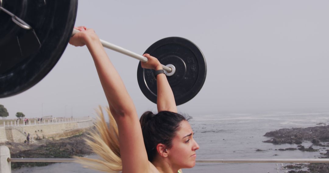 Determined Woman Weightlifting Outdoors Near Ocean - Free Images, Stock Photos and Pictures on Pikwizard.com