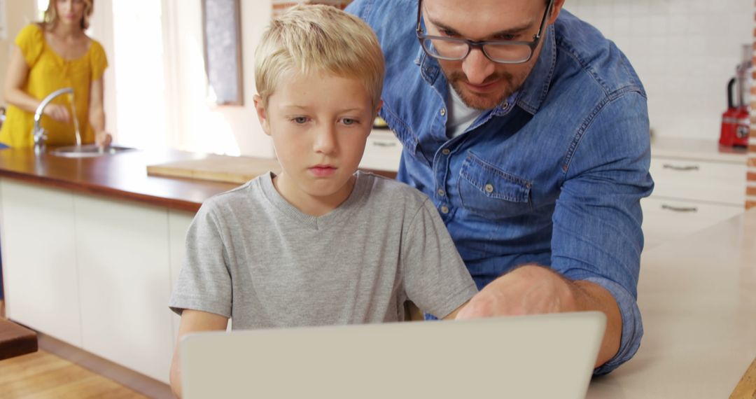 Father Helping Son with Homework on Laptop in Kitchen - Free Images, Stock Photos and Pictures on Pikwizard.com