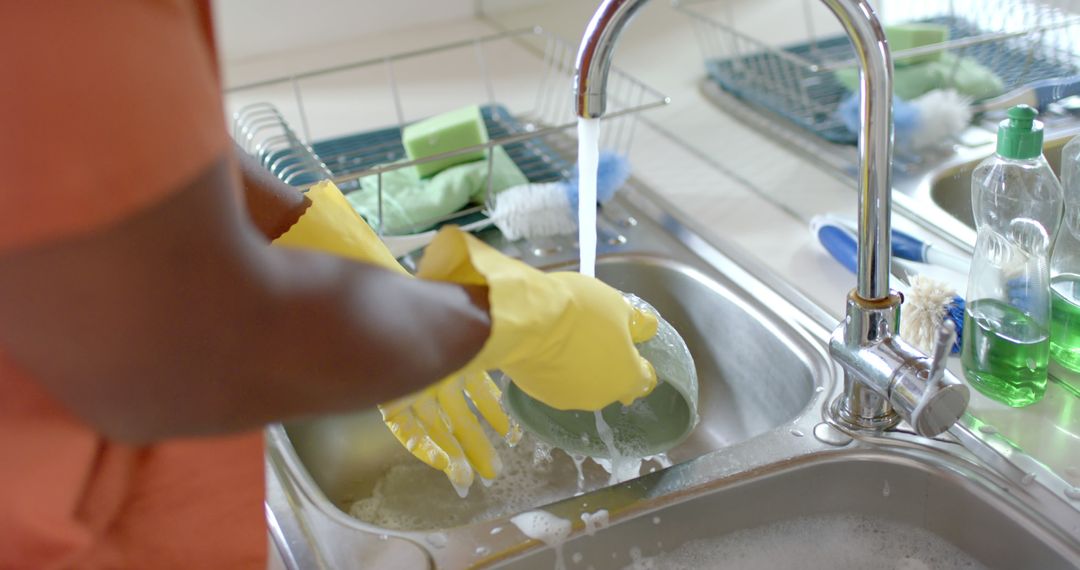 Close-up of Person Washing Dishes with Yellow Gloves in Modern Kitchen - Free Images, Stock Photos and Pictures on Pikwizard.com